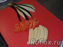 Разрезать баклажан на полоски веером, не дорезая до конца. Полукольцами нарезать помидор. Тонкими ломтиками нарезать сыр.