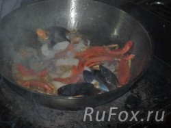 Обжарить на растительном масле морской гребешок, хвостики тигровых креветок, лук, помидоры и мидии.