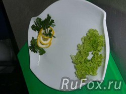 Украсить тарелку лимоном, зеленью и листьями салата.